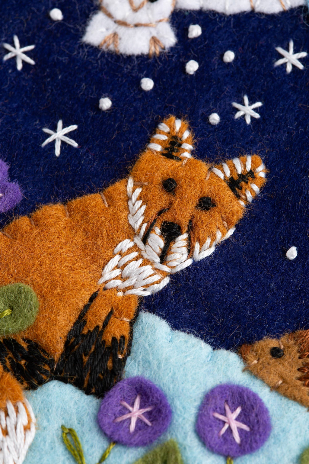 Felted fabric with embroidered fox and star patterns on a dark blue background