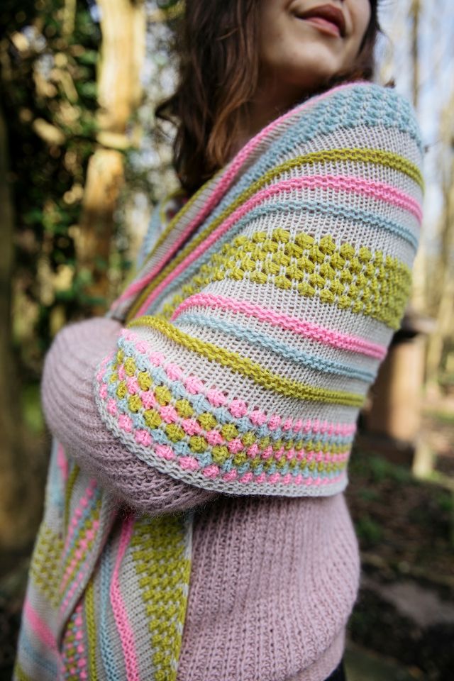Person wearing a colorful, patterned shawl in a natural setting