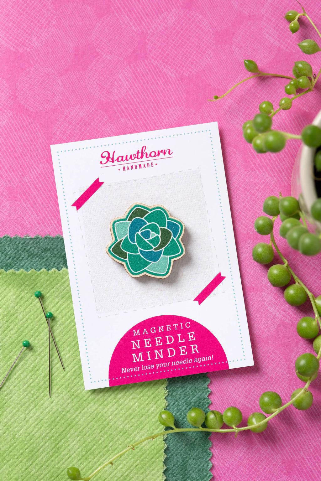 Magnetic needle minder with succulent design on a card against a pink and green background