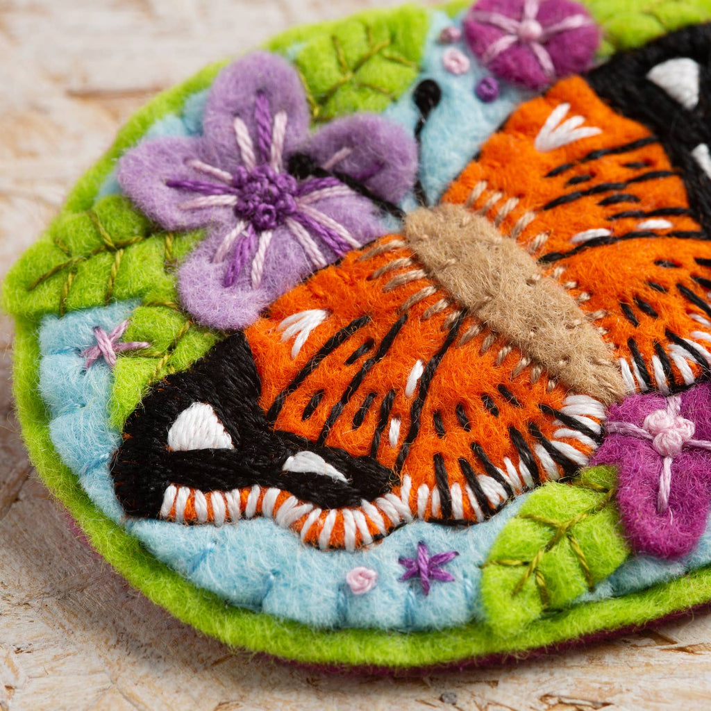 Embroidered brooch with a butterfly and flowers on a wooden surface