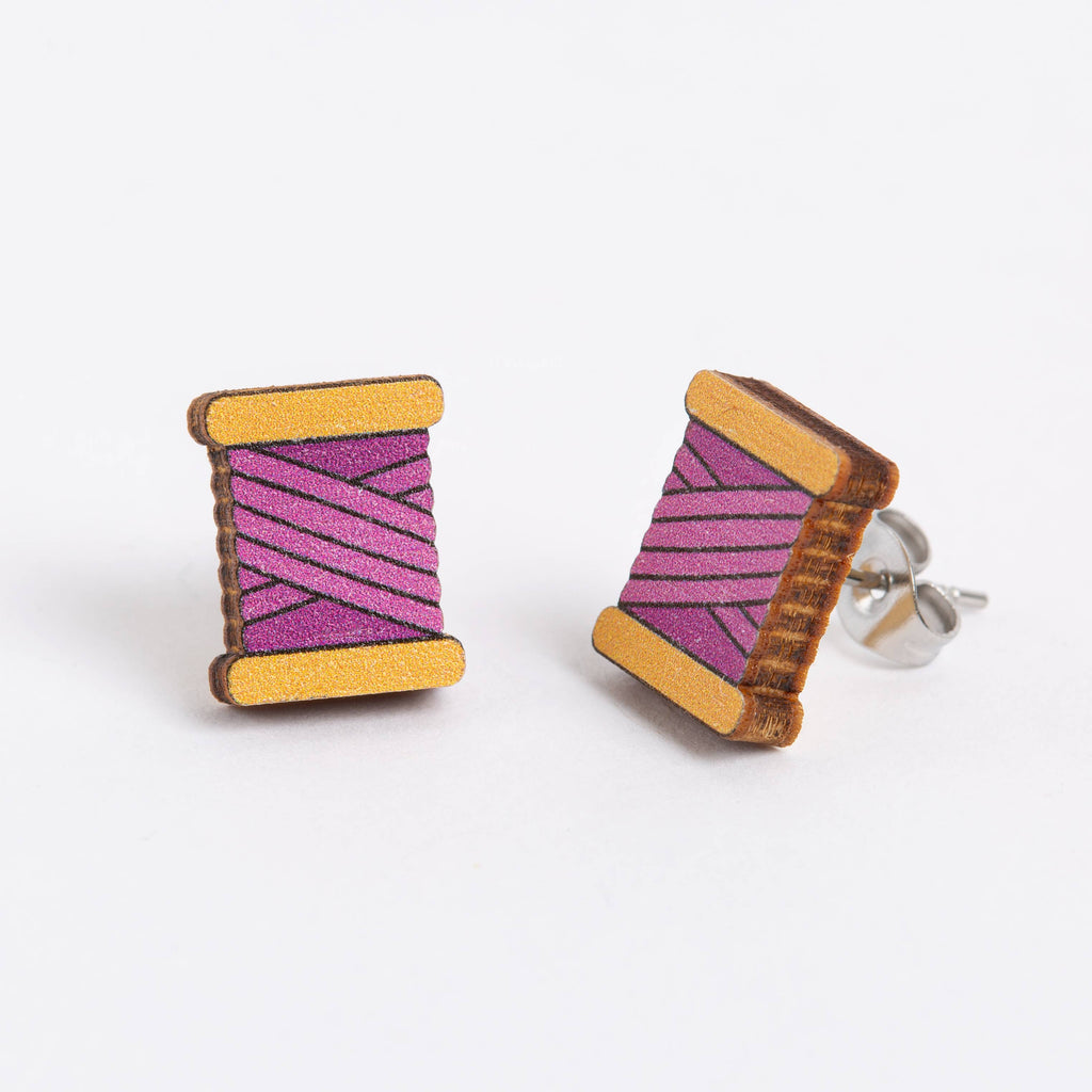 Wooden spool earrings with purple thread design on a white background