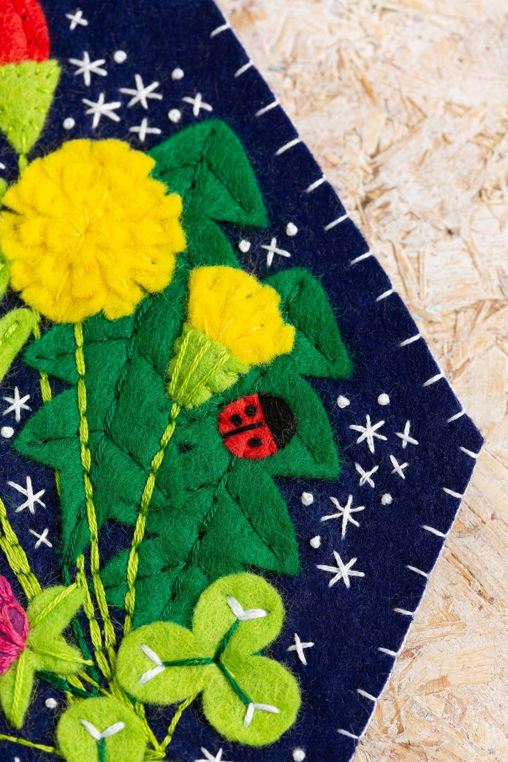 Embroidered patch with flowers, ladybug, and shamrock on a dark blue background.