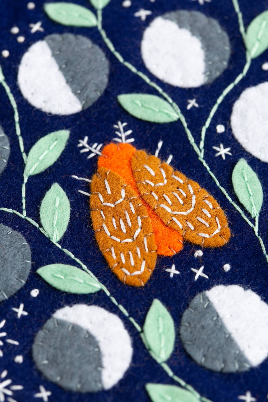 Fabric with orange moth design on a navy background with moon phases and leaves